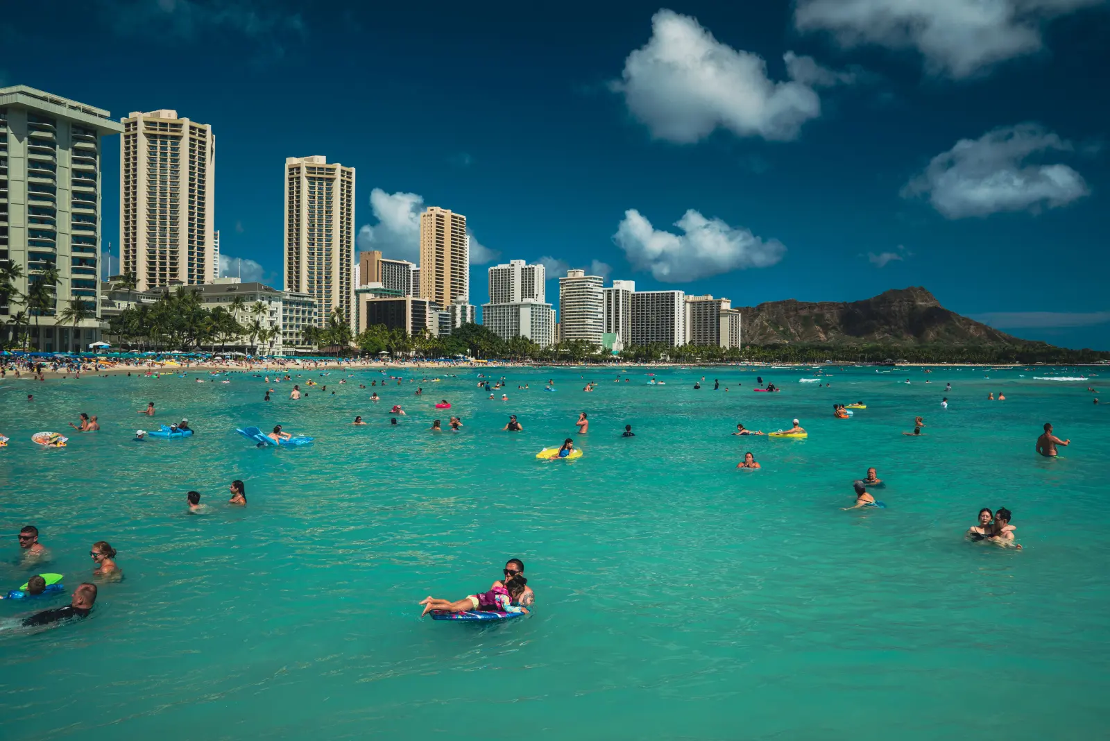 Families enjoying sunny Waikīkī Beach with Diamond Head in view